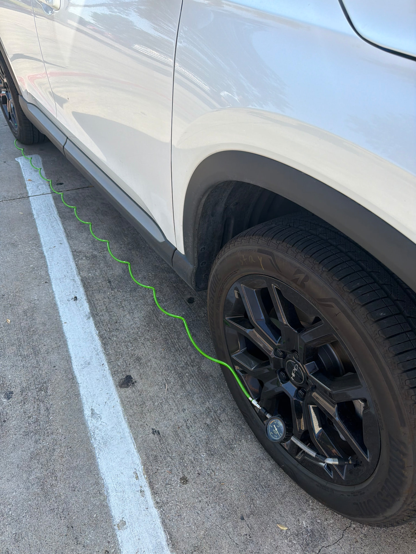 Air hose and pressure gauge connected to a vehicle tire during mobile roadside tire-air service in the DFW Metroplex