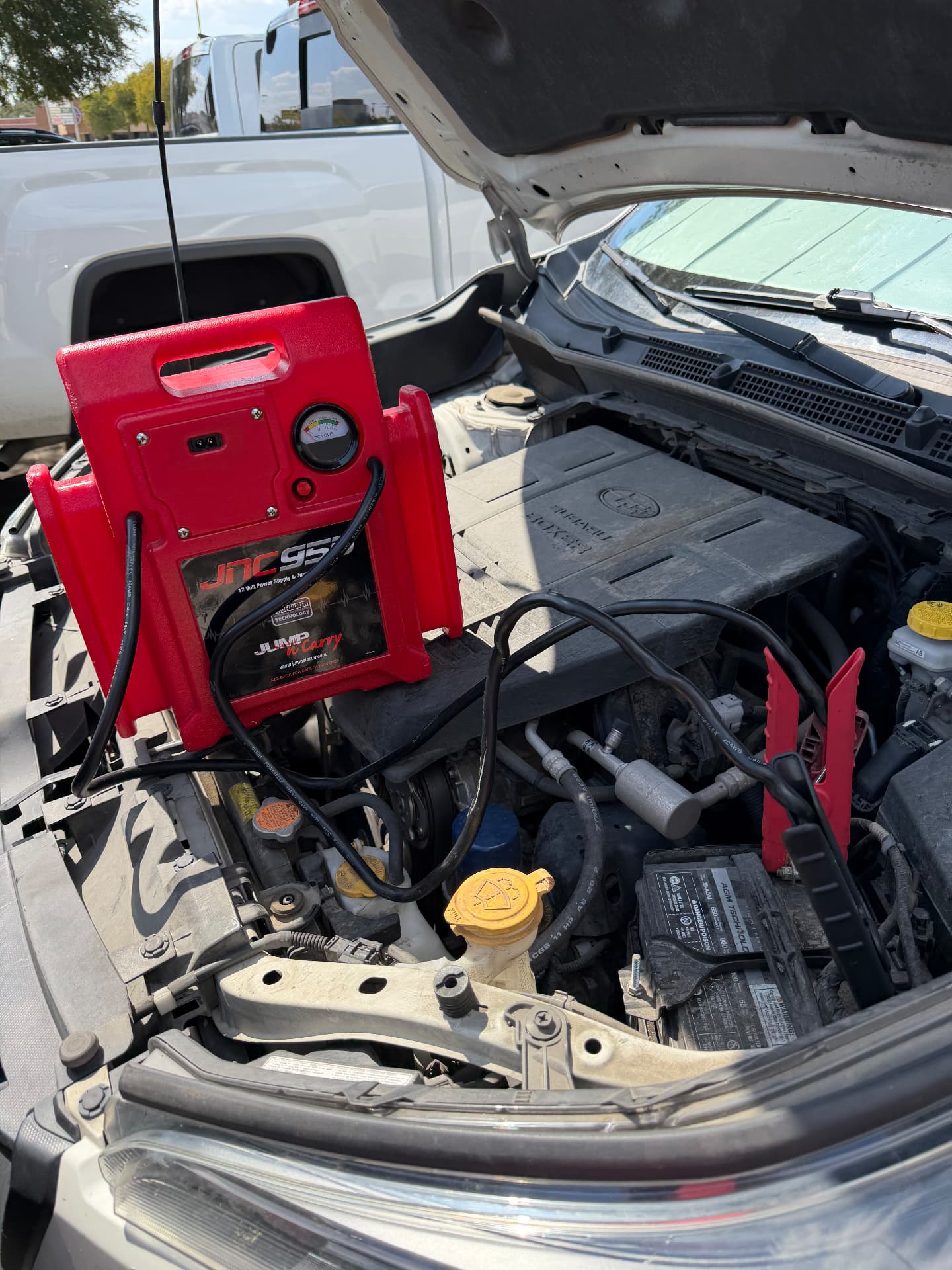 Portable jump start in Irving, TX 75038 Red portable jump pack connected under the open hood of a vehicle during a roadside jump start in Irving, Texas 75038
