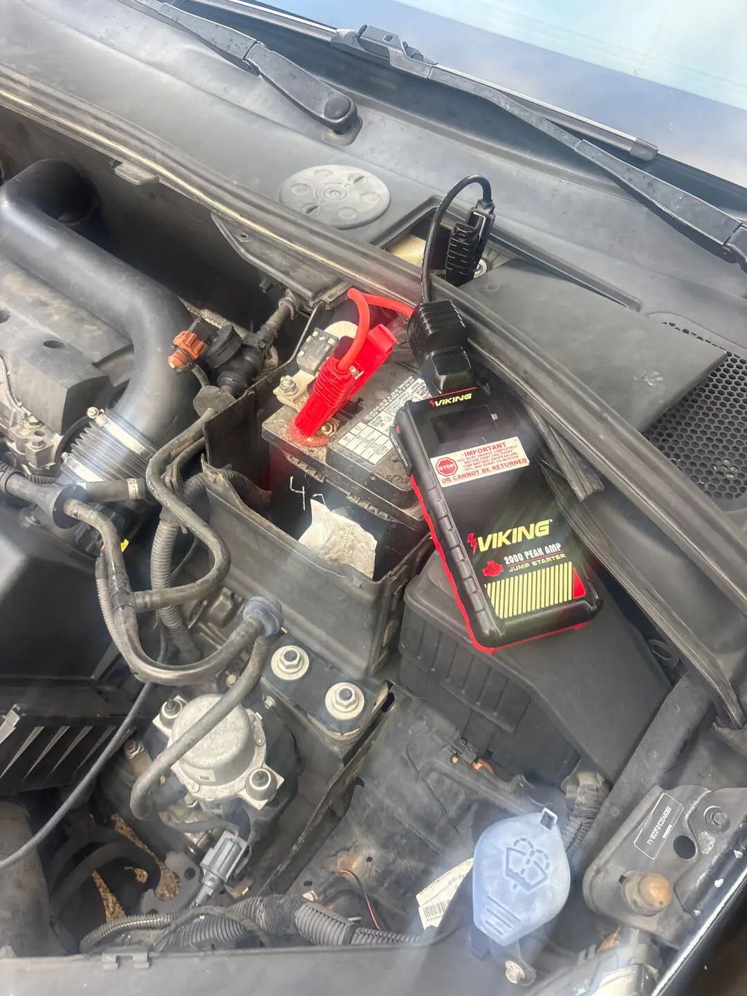 Viking 2000 peak amp lithium jump pack clamped to a car battery in an open engine bay during a DeSoto, Texas 75115 roadside jump start