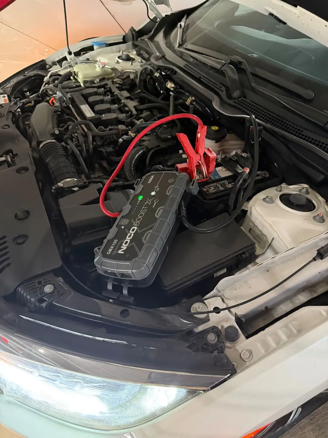 Jump start on a Honda Civic in Euless, TX 76040 NOCO Boost X GBX155 lithium jump pack clamped to the battery of a white Honda Civic with the hood open during a roadside jump start in Euless, Texas