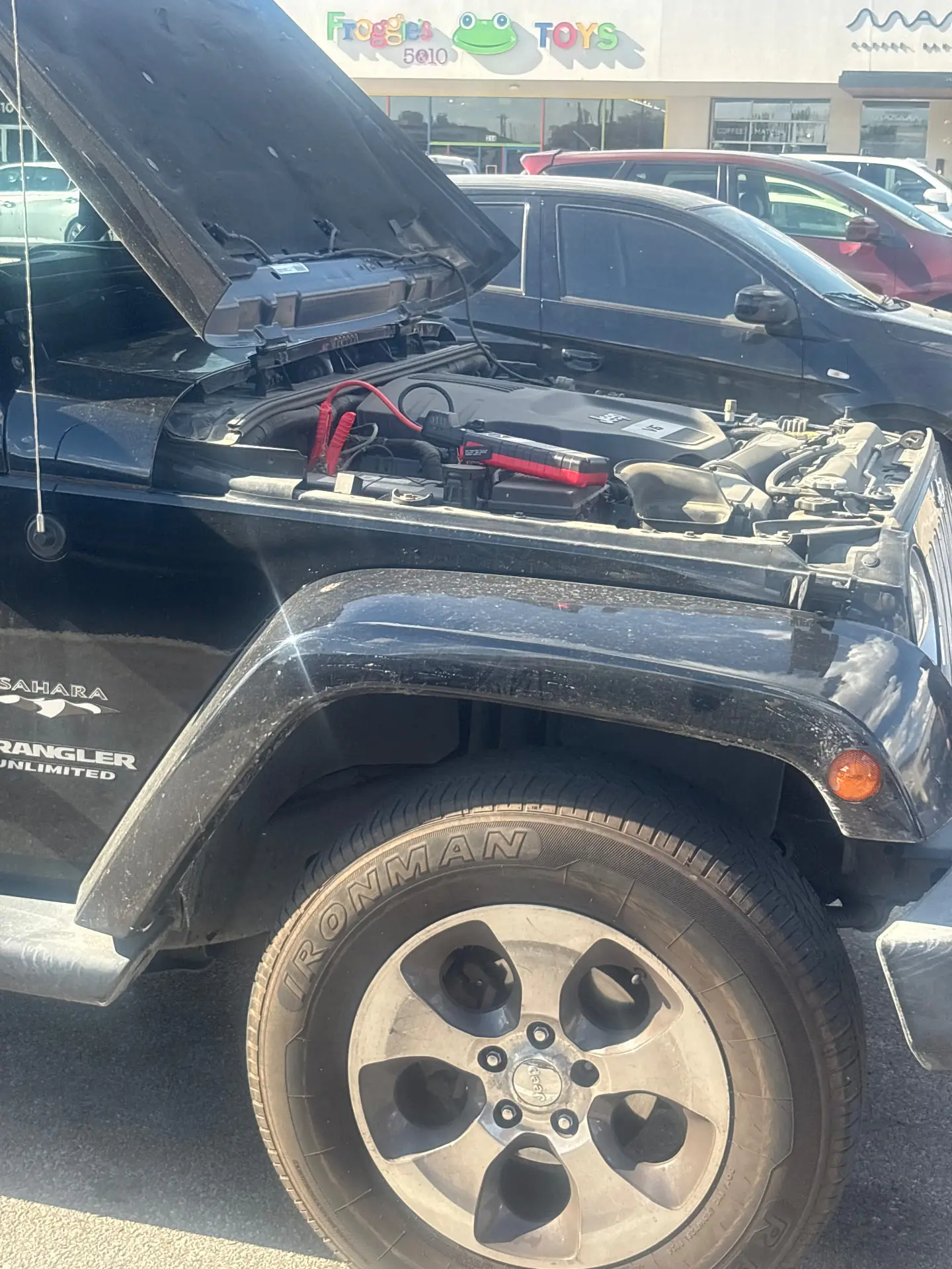 Portable lithium jump pack connected to the battery of a Jeep Wrangler with the hood open during a Fort Worth roadside jump start