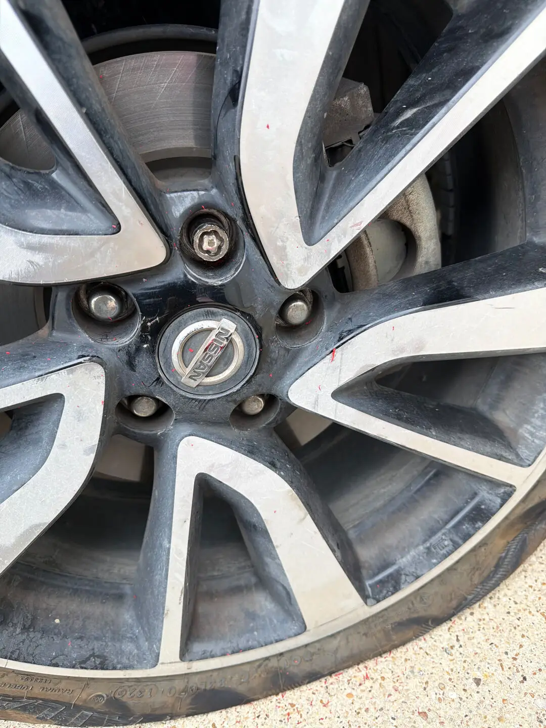Missing wheel lock key removal in Fort Worth, TX 76102 Close-up of a Nissan alloy wheel with a locking lug nut being removed after the wheel lock key went missing, during a Fort Worth, Texas 76102 roadside tire repair